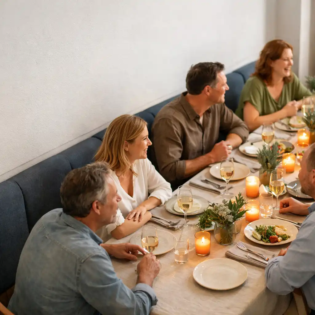 Friends gathered around a shared dinner table in Sable & Willow's bright restaurant setting